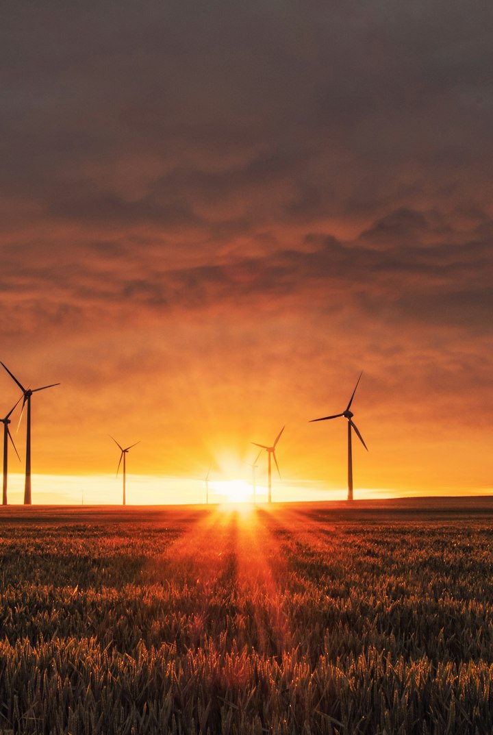 Wind turbines generating power over open fields at sunset